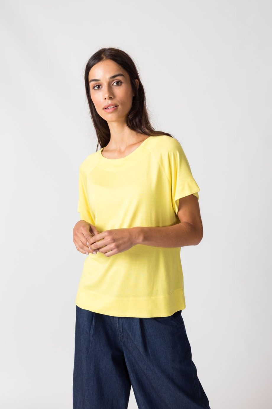 Frau trägt Basic Shirt von SKFK (NAHIERA) aus recycelter Viskose in Zitronengelb mit kurzen Raglanärmeln, Rundhals-Ausschnitt und abgerundetem Saum. / pussyGALORE / Leipzig